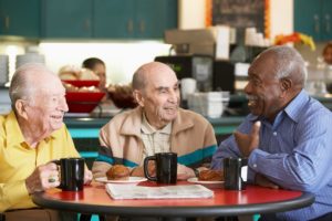 three elderly men having coffee