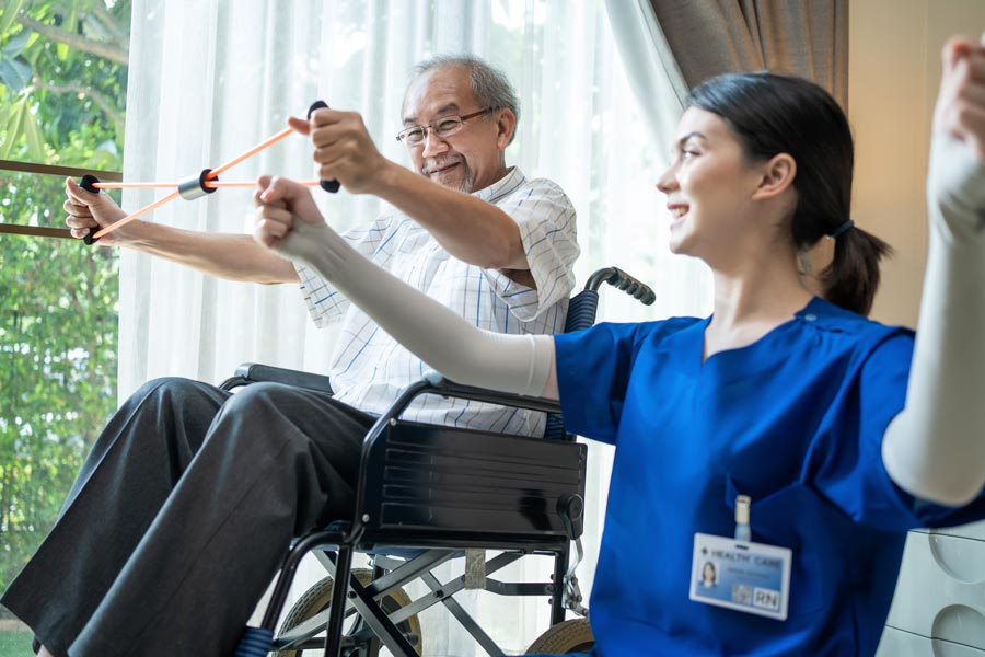 nurse helping elderly in wheelchair with exercise