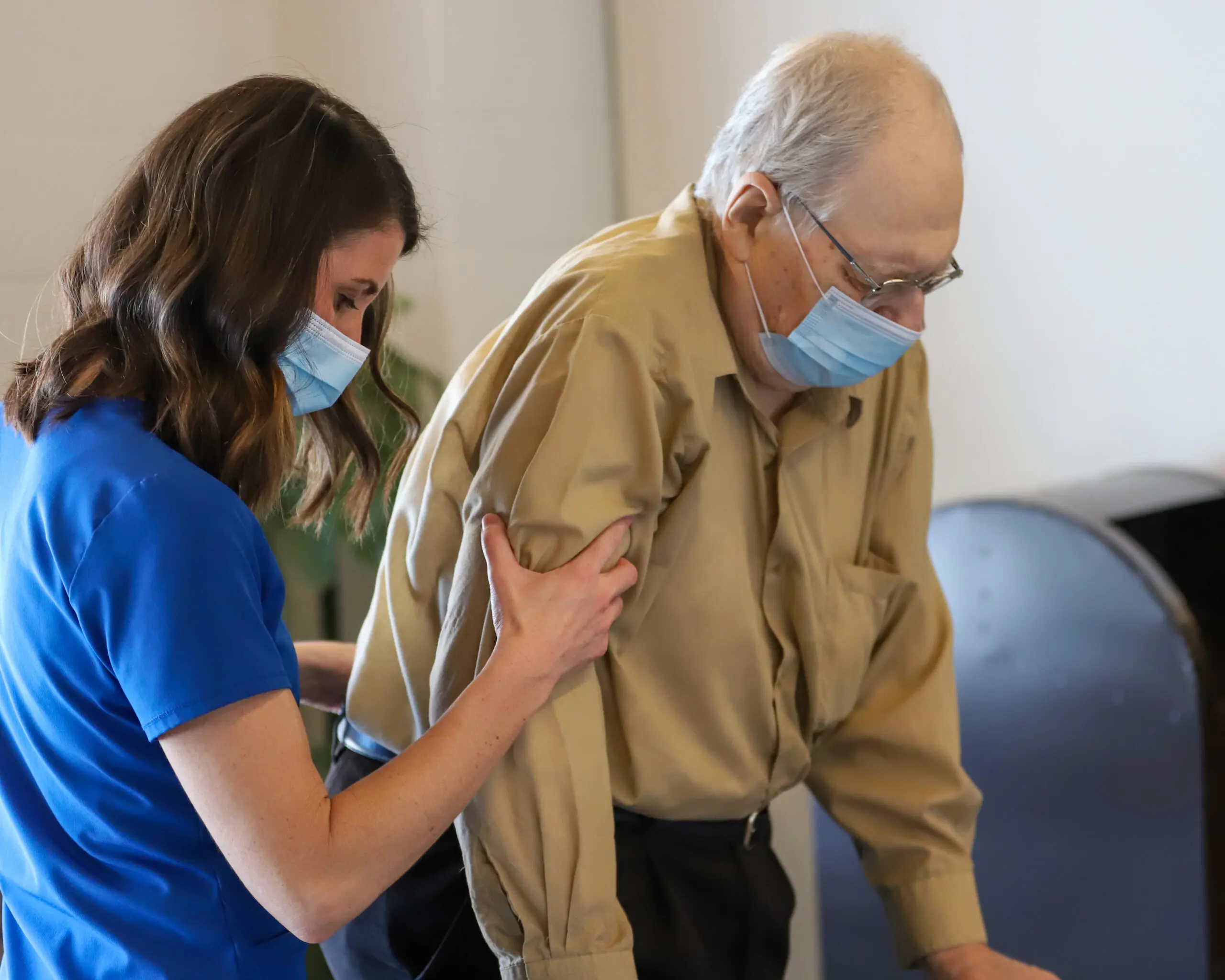 Health care professional helping an elderly man walk.